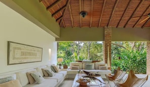 A room with a white sofa, a coffee table, and a view of lush greenery outside. - Fabulous 4-bedroom house in charming Nilo perfect for your getaway (Nilo)