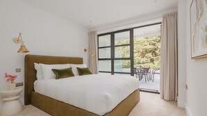 Una camera da letto con un letto grande, un comodino, una lampada e vista su una zona esterna.