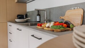 Una cucina moderna con un lavello in acciaio inossidabile, un tagliere di legno con verdure e una bottiglia di vino.