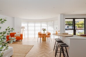 Un soggiorno moderno con zona pranzo, un bancone cucina e un'ampia finestra con vista.