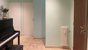 Ein Zimmer mit einem Klavier, einer Heizung und einer Tür.