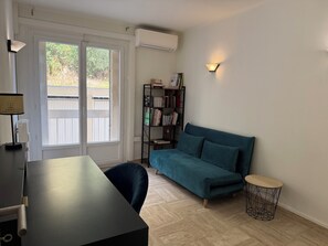 Une pièce comprenant un canapé, une table, une bibliothèque et une lampe.
