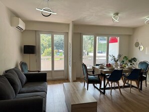 Una sala de estar con sofá, mesa de comedor, sillas y televisor.