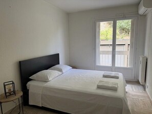 Un dormitorio con una cama, una mesita y una ventana con vistas al exterior.