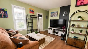 A living room with a sofa, a coffee table, a TV stand, and a bookshelf.