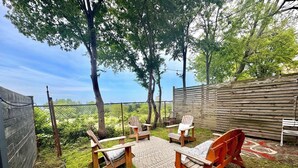 An outdoor seating area with wooden chairs and a table, surrounded by a wooden fence and trees.