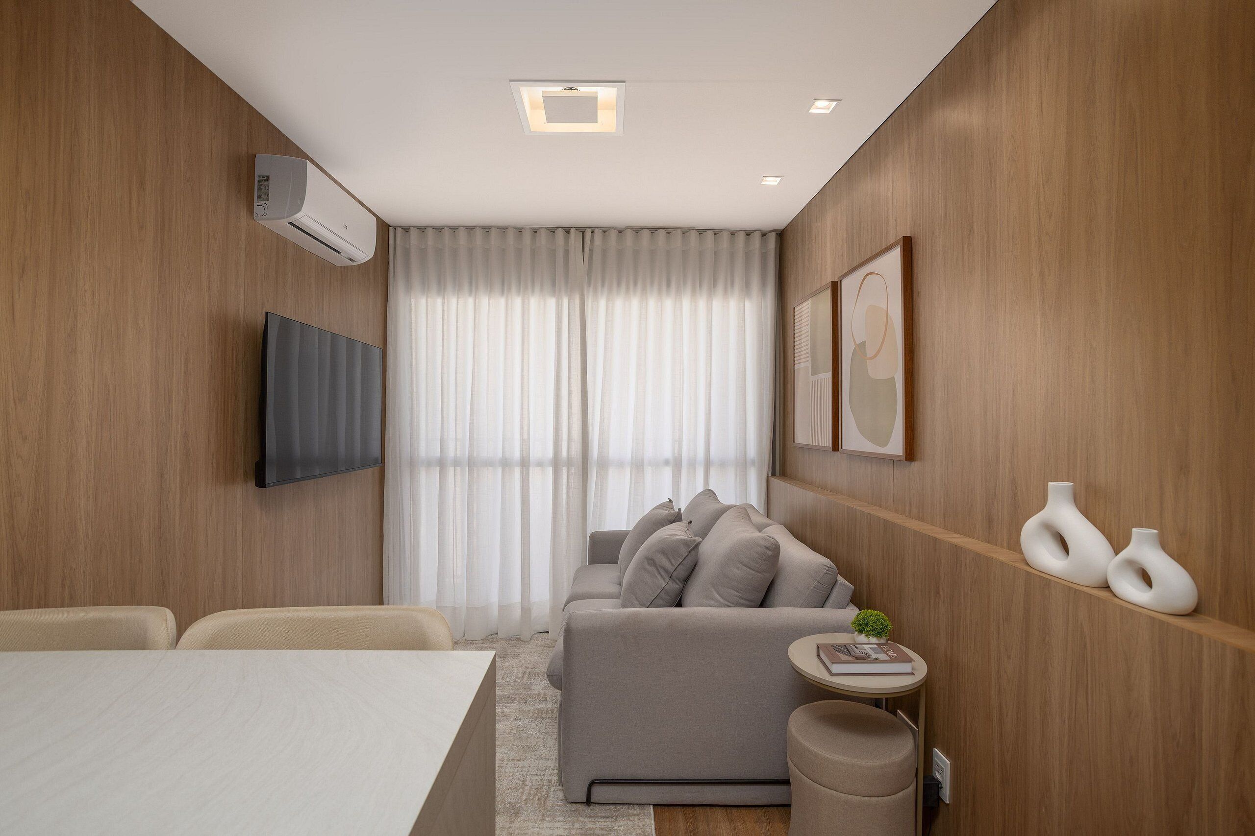 Una sala de estar moderna con un sofá, un televisor de pantalla plana y una pequeña mesa redonda con un libro.
