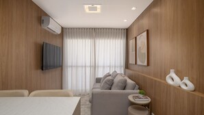 A modern living room with a sofa, a flat-screen TV, and a small round table with a book. - ON Augusta (São Paulo)