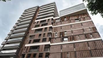 Um edifício de vários andares com design arquitetônico moderno, com varandas e grandes janelas.