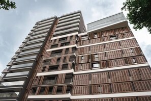 Um edifício de vários andares com design arquitetônico moderno, com varandas e grandes janelas.