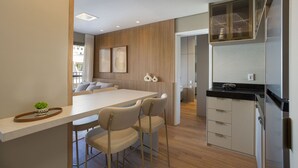 A modern kitchen with a central island, bar stools, and a built-in oven. - ON Augusta (São Paulo)