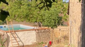 Una piscina con una escalera, cerca una valla de madera y una silla.