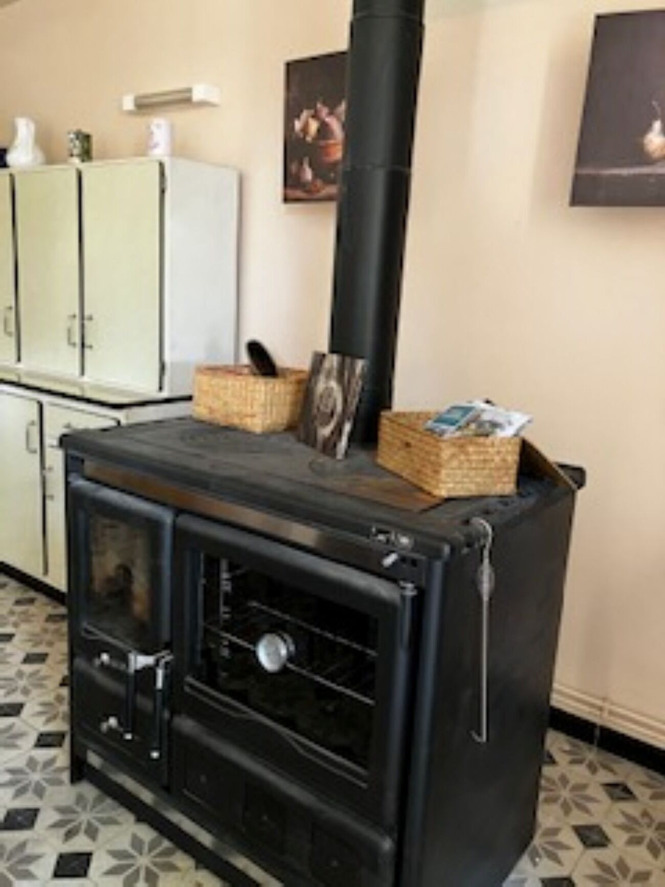 Una cocina con estufa negra, armarios y piso de baldosas.