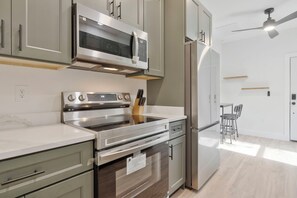 A modern kitchen with stainless steel appliances, a built-in oven, and a refrigerator. - M Street Loft - One-of-a-Kind Pensacola Getaway (Pensacola)