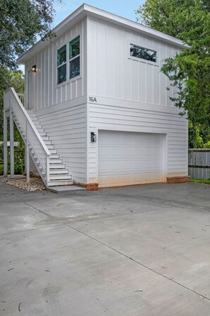A single-story building with a garage, a staircase leading to the entrance, and a number '16A' on the side. - M Street Loft - One-of-a-Kind Pensacola Getaway (Pensacola)