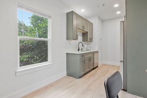 A modern kitchen with a window, built-in cabinets, and a countertop. - M Street Loft - One-of-a-Kind Pensacola Getaway (Pensacola)