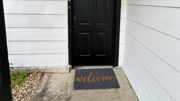 A black door with a welcome mat, a house number 2162, and a small outdoor light fixture. - Welcoming 2-bedroom house with AC in Arlington, near AT&T Stadium &Six Flags (Arlington)
