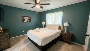A bedroom with a bed, nightstands, a ceiling fan, and a wall-mounted lamp. - Welcoming 2-bedroom house with AC in Arlington, near AT&T Stadium &Six Flags (Arlington)