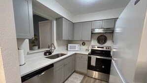 A compact kitchen with a built-in microwave, stainless steel appliances, and a white countertop. - Welcoming 2-bedroom house with AC in Arlington, near AT&T Stadium &Six Flags (Arlington)