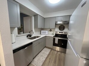 A compact kitchen with a built-in microwave, stainless steel appliances, and a white countertop. - Welcoming 2-bedroom house with AC in Arlington, near AT&T Stadium &Six Flags (Arlington)