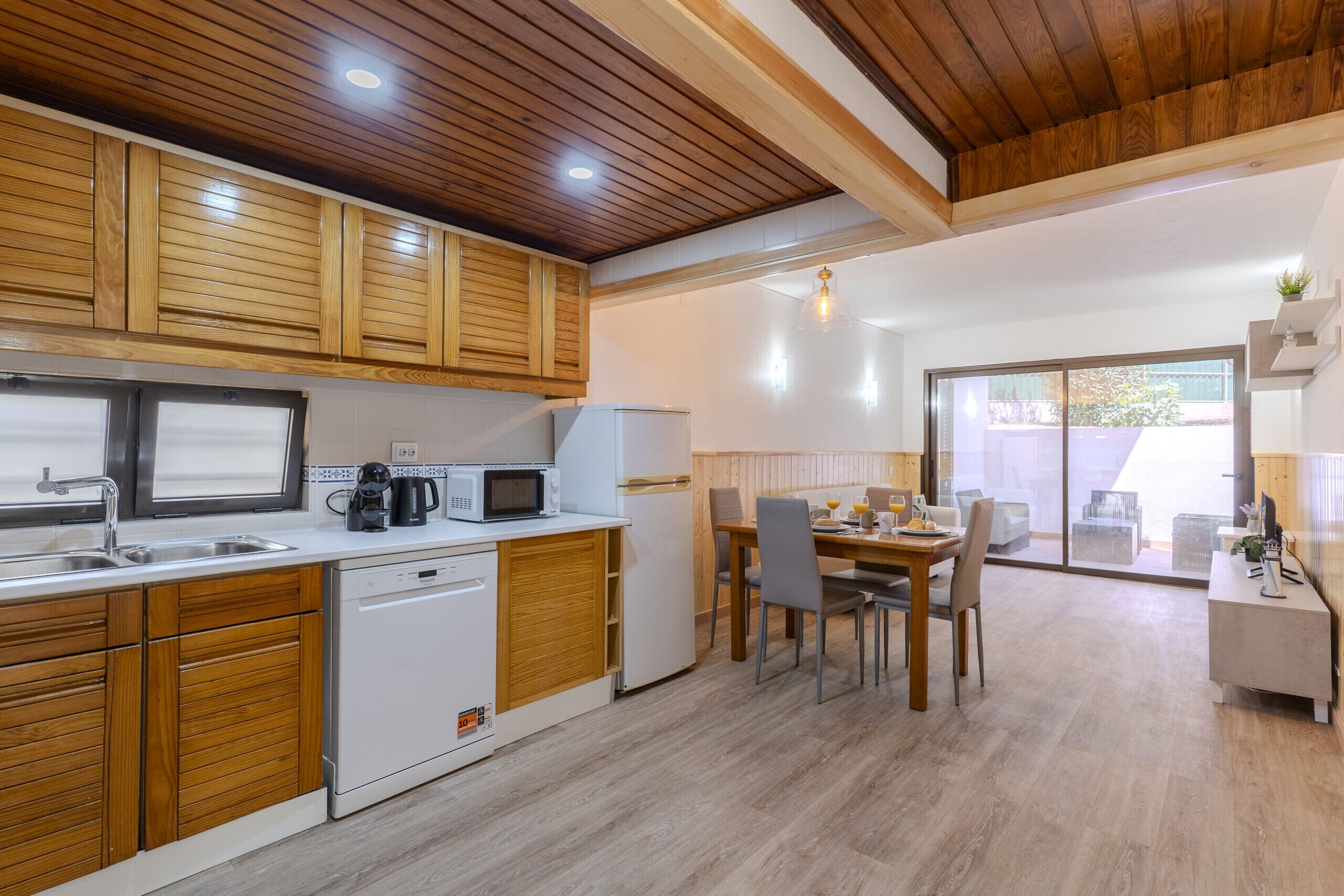 A modern kitchen with wooden cabinets, a dishwasher, and a dining area with a table and chairs.