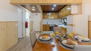 A modern kitchen with wooden cabinets, a dining table set for breakfast, and a visible fire extinguisher. - #400 Central Albufeira Oasis | 1BR & Pool (Albufeira)