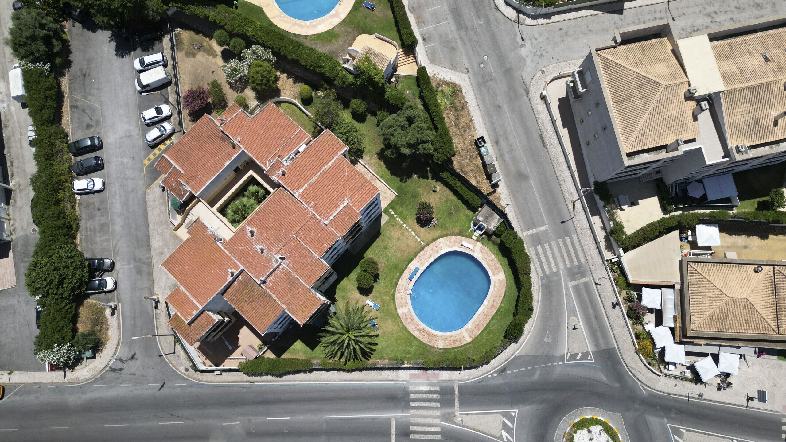 Una vista aerea di una zona residenziale con un grande edificio dotato di cortile e due piscine.