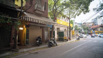 Vista de la calle con edificios, una moto estacionada y un letrero amarillo.