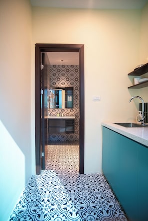 A narrow hallway with patterned floor tiles leading to a kitchen area with a sink and cabinets. - DoDo Apartments (Ha Noi)