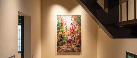 A staircase with a wooden handrail leading to a landing with a wall-mounted painting.