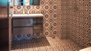 Un baño con baldosas estampadas, un lavamanos, un espejo y una zona de ducha.