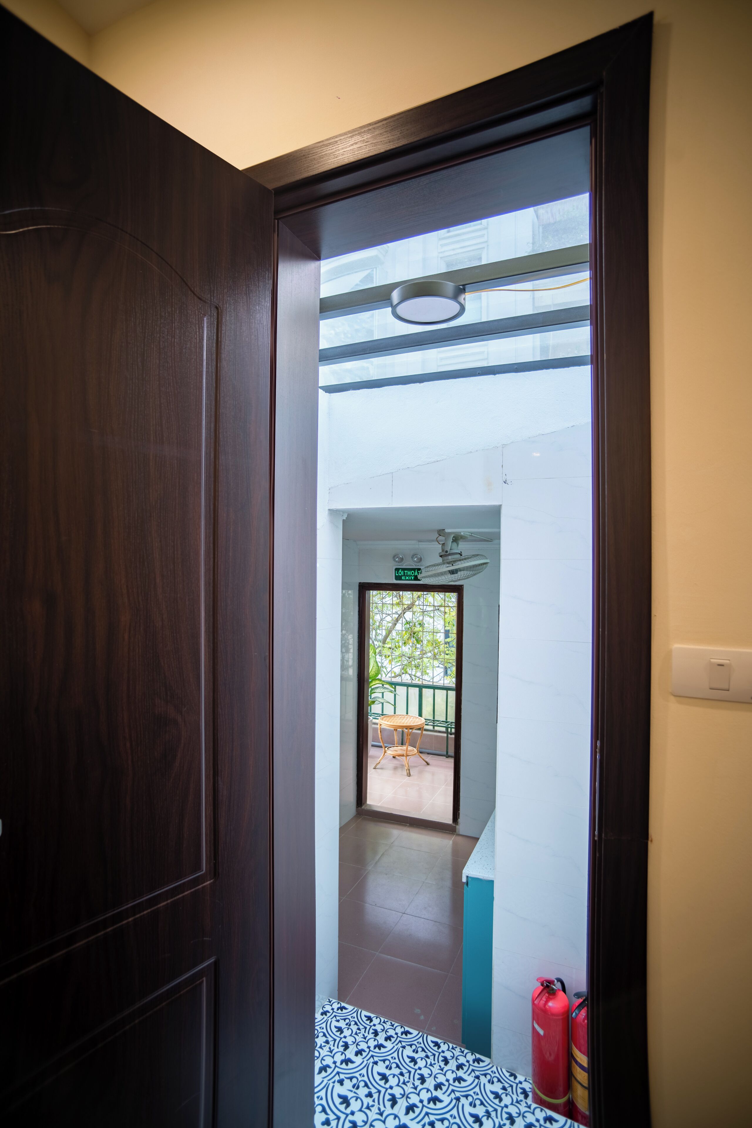 A doorway leading to an outdoor area with a tiled floor, a fire extinguisher, and a sign indicating an exit.