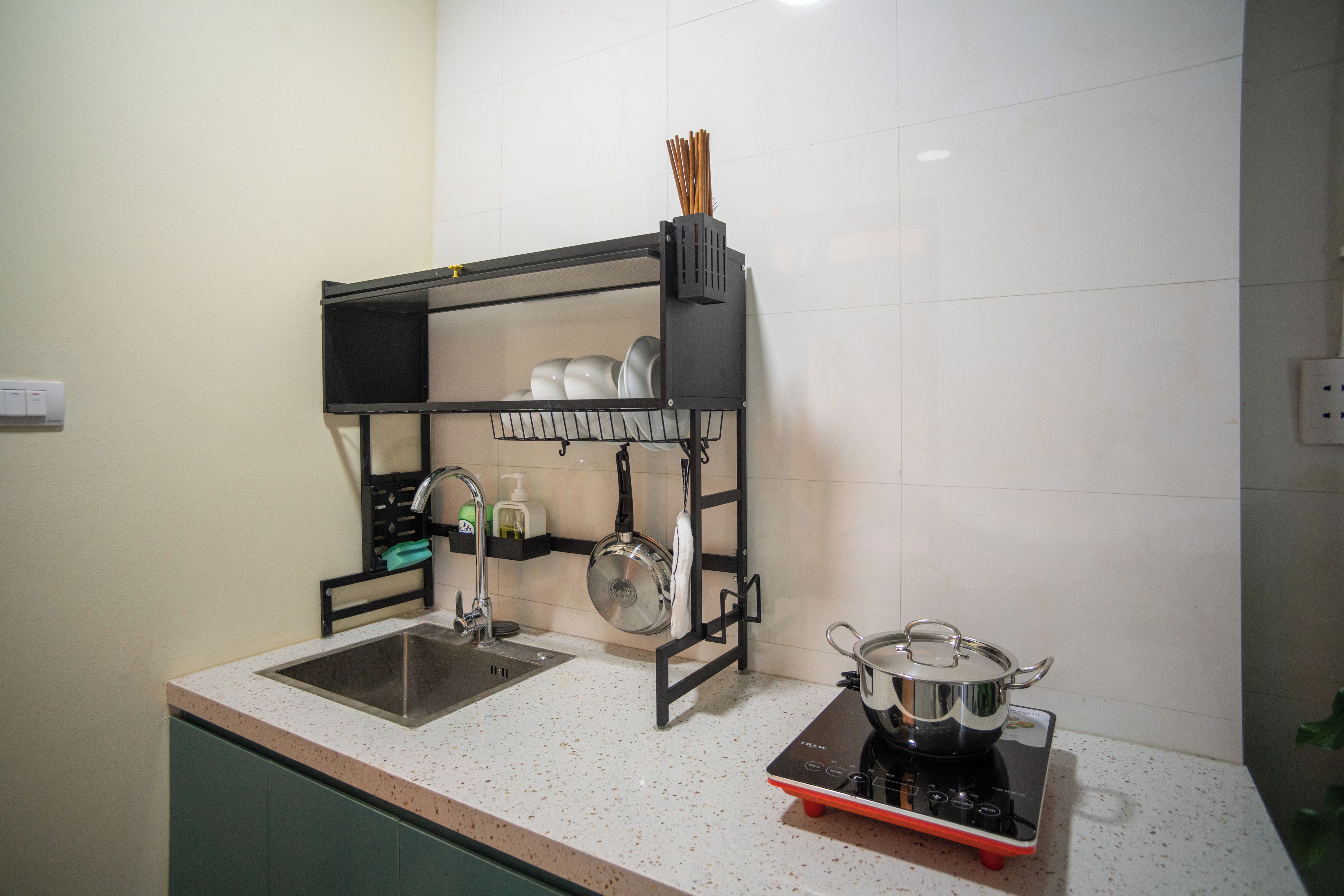 A kitchen with a double sink, a black hanging rack with dishes, a stove, and a pot on the counter.