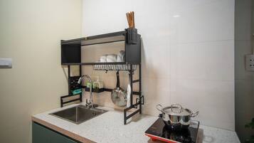 A kitchen with a double sink, a black hanging rack with dishes, a stove, and a pot on the counter.
