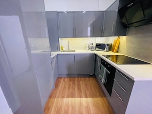 A modern kitchen with grey cabinets, a stainless steel microwave, and a wooden floor. - Apartment Sleeps 4 - Wifi, Close to Football Club (Ipswich)