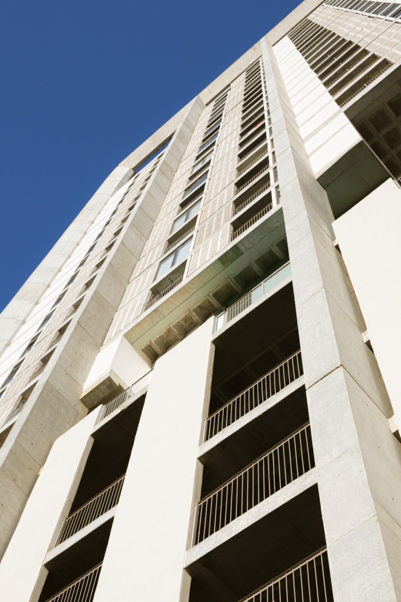 A tall building with multiple floors, large windows, and a clear sky.