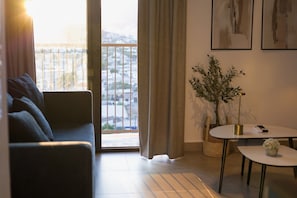 Een woonkamer met een bank, een klein rond tafeltje, een potplant en uitzicht door een schuifdeur.