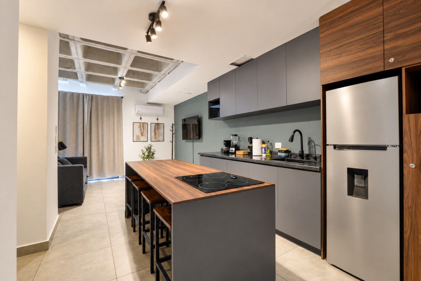 Una cocina moderna con una isla central, electrodomésticos de acero inoxidable y diseño de muebles grises.