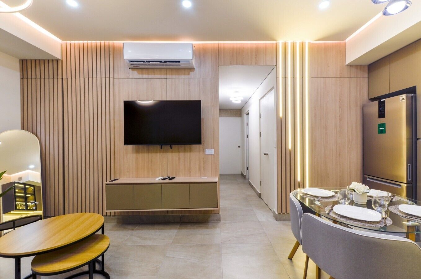 Une chambre d’hôtel moderne dotée d’une télévision à écran plat, d’un climatiseur intégré, d’un coin repas avec une table en verre et d’un mini-bar.