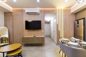 A modern hotel room with a flat-screen TV, a built-in air conditioner, a dining area with a glass table, and a minibar. - ¡Céntrico & Nuevo! Gym, Parking & Pool - 6G 2BR2br (Monterrey)