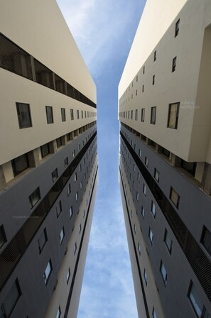 A symmetrical building with multiple floors and windows, viewed from a low angle looking up. - ¡Céntrico & Nuevo! Gym, Parking & Pool - 6G 2BR2br (Monterrey)