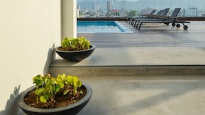 A rooftop terrace with a pool, lounge chairs, and a view of a city skyline. - ¡Céntrico & Nuevo! Gym, Parking & Pool - 2BR2br 6G (Monterrey)