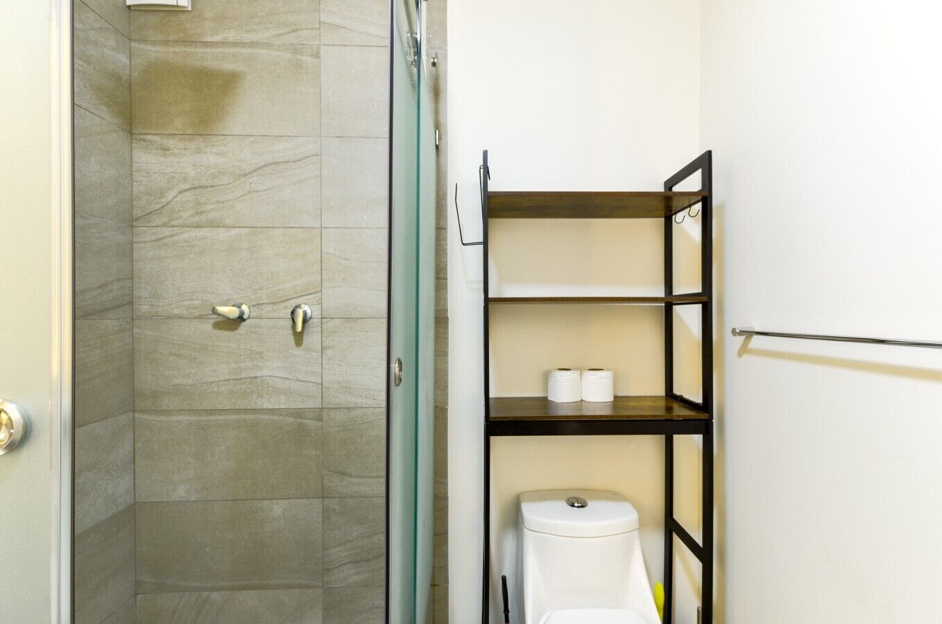 Ein Badezimmer mit Dusche, Toilette und Regalen.