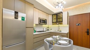 A modern kitchen with a built-in microwave, a stainless steel refrigerator, and a dining area with a glass table and chairs. - ¡Céntrico & Nuevo! Gym, Parking & Pool - 2BR2br 6G (Monterrey)