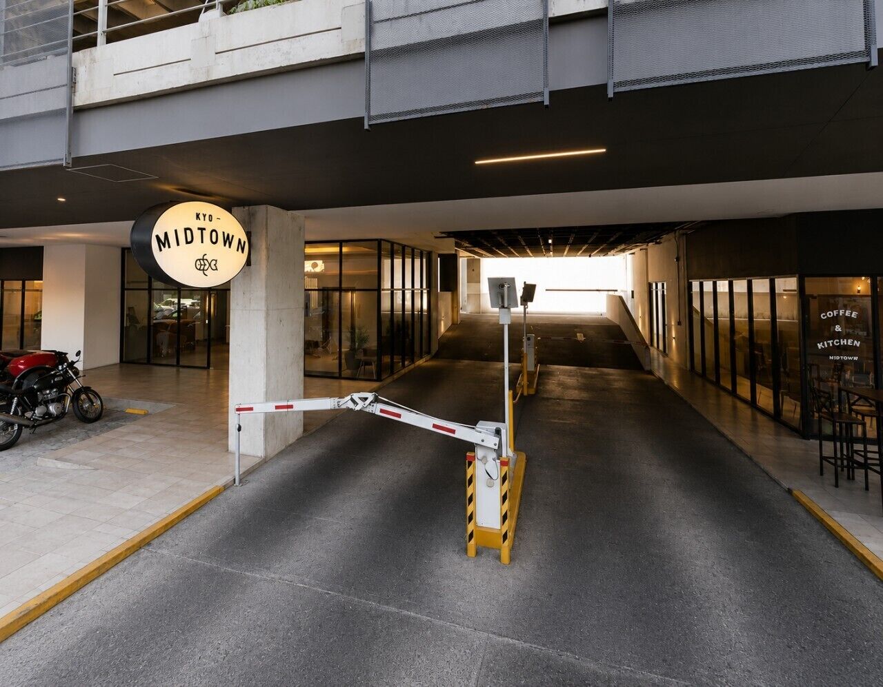 Un bâtiment moderne avec une enseigne indiquant « KYO - MIDTOWN » et un café appelé « COFFEE & KITCHEN MIDTOWN » situé sur la droite.