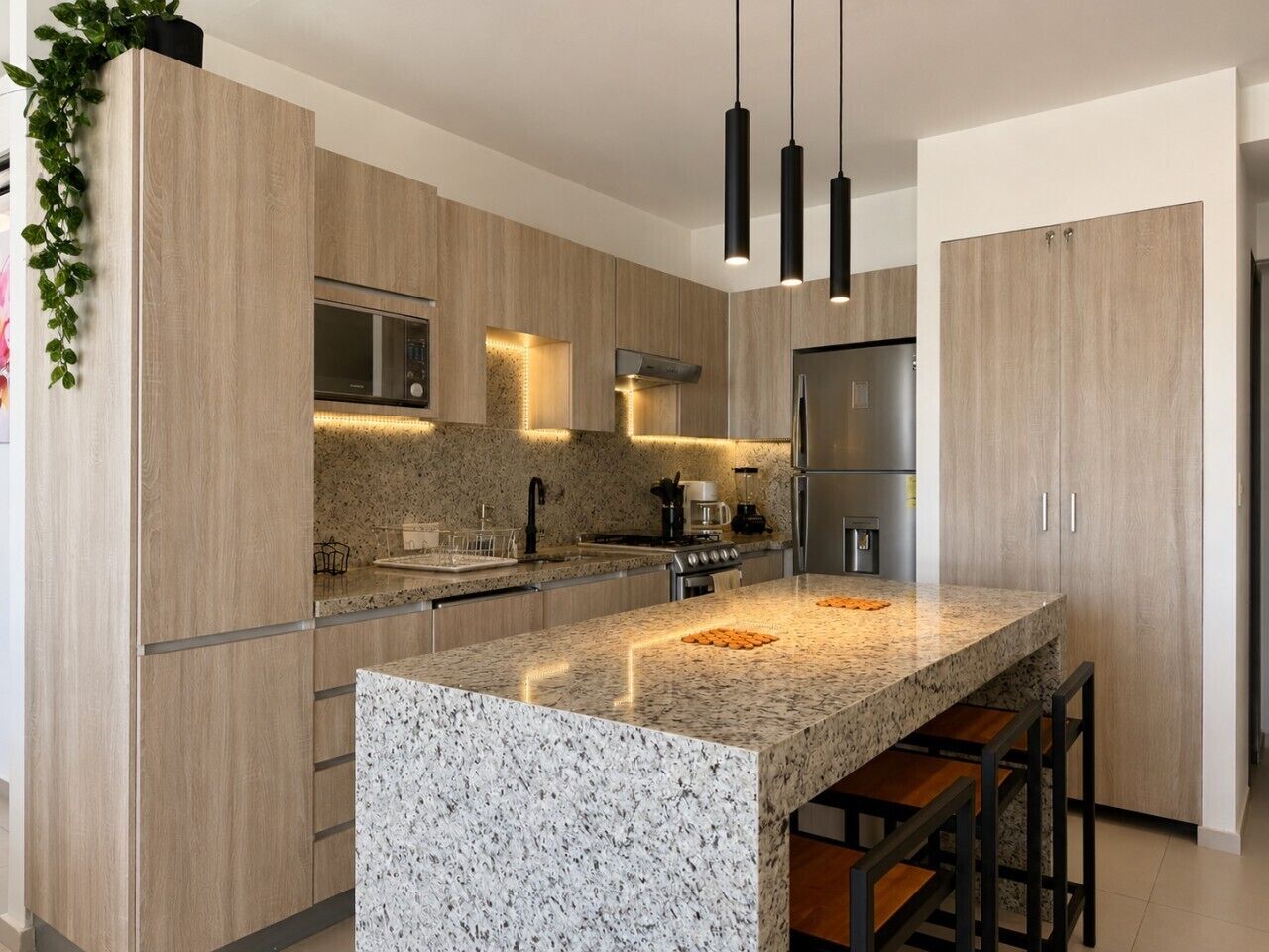 A modern kitchen with a granite island, stainless steel appliances, and pendant lighting.