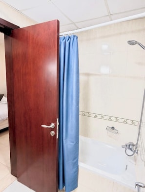 A wooden door with a blue curtain partially drawn, leading to a bathroom with a shower and a tiled wall.