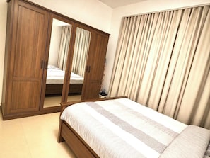 A bedroom with a bed, a wardrobe, and curtains.