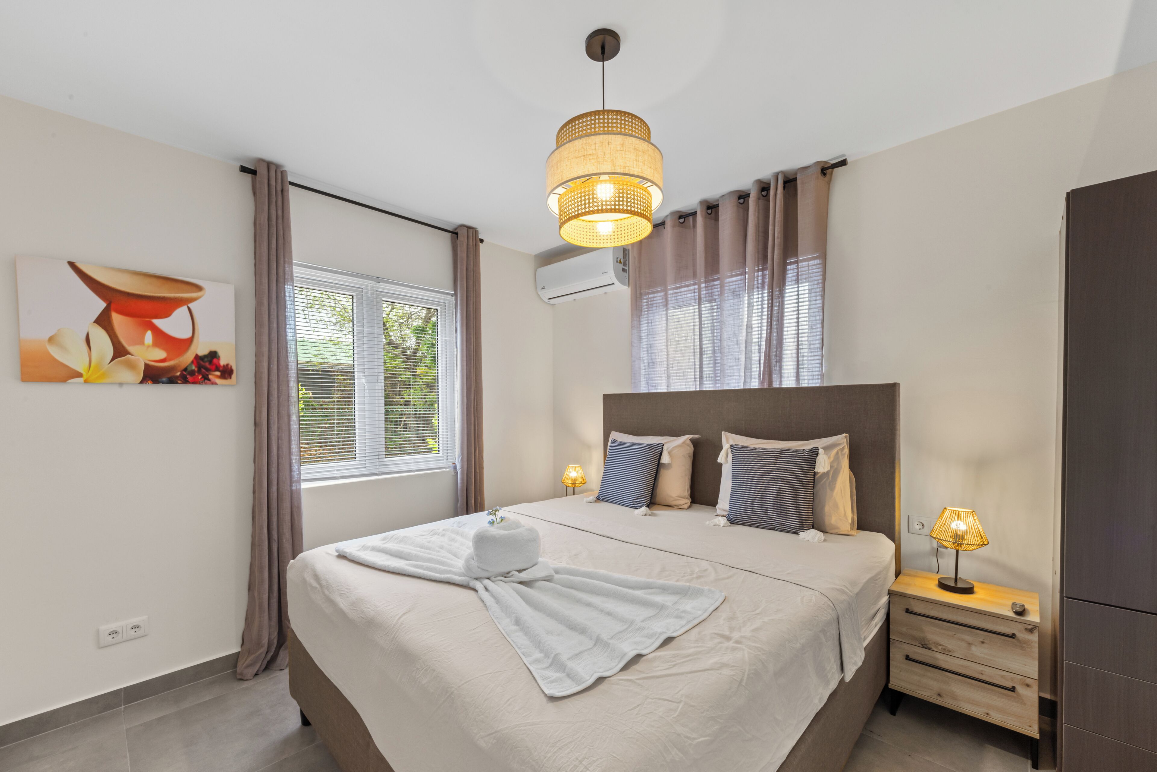 Ein Hotelzimmer mit Bett, Nachttischlampe und einem Gemälde an der Wand.