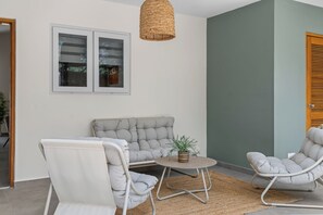 A room with a grey sofa, two white chairs, a small round table with a plant, and a woven light fixture. - 4-person vacation bungalow with shared pool (Willemstad)